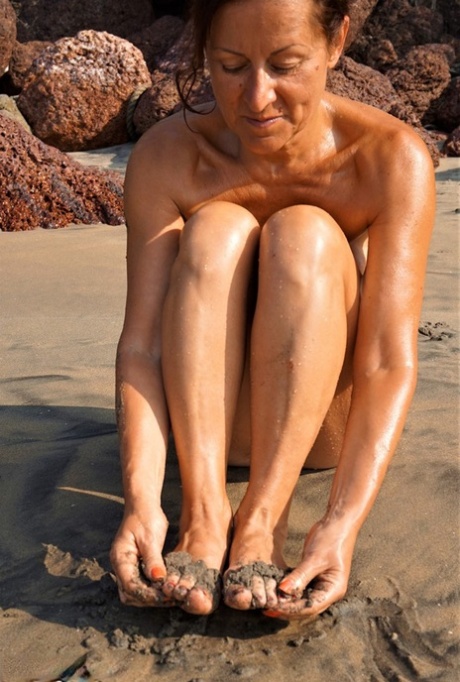 Naked Older Woman Diana Ananta Covers Her Feet In Beach Sand At Low