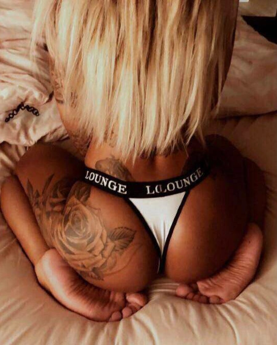 La jeune femme amatrice tatouée se montre aguicheuse avec son décolleté et  ses fesses en string. - NakedPics