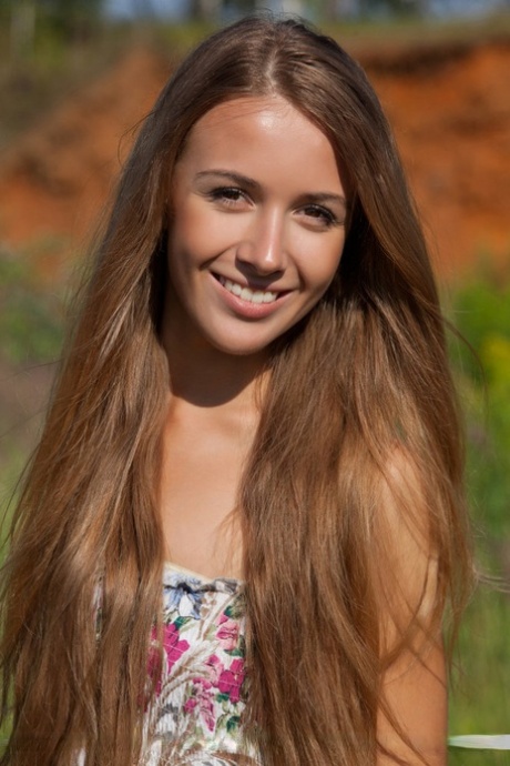 La flaca adolescente de pelo largo Lina se despoja de su colorido vestido en el exterior