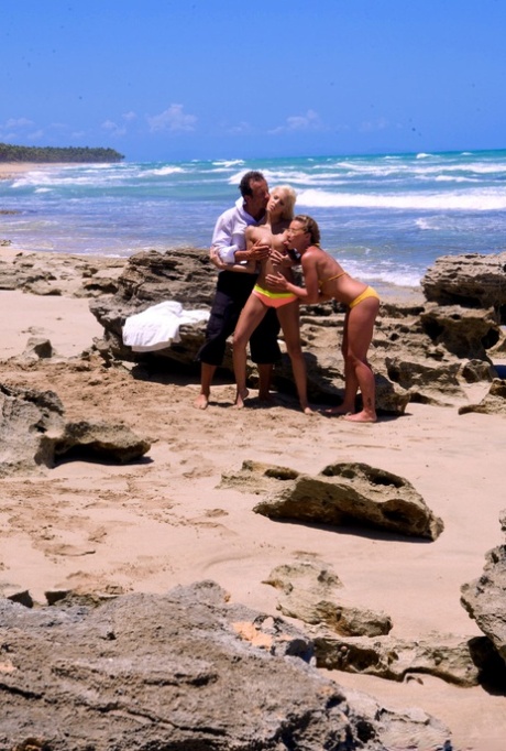 Zwei Mädchen und ein Gentleman-Freund haben einen Dreier an einem Sandstrand