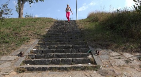 Die verstörte Kayla zieht ihre rosa Leggings aus, um auf die Steinstufen zu pinkeln