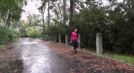 Den mörkhåriga flickan Goldie drar ner svarta leggings för att kissa bredvid skogen