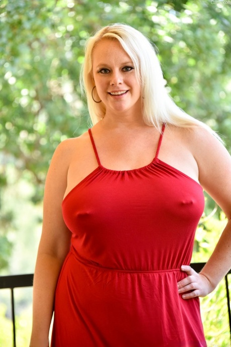 Piercet moden fedling i rød kjole viser nøgen nederdel og blotter enorme bryster