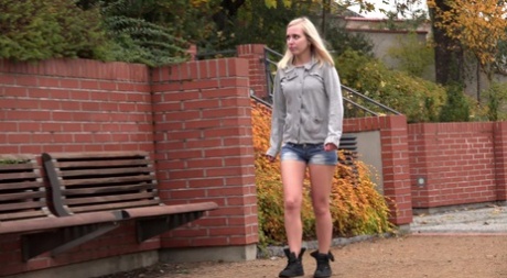 Blondes Mädchen Debora zieht Jeans-Shorts aus, um auf einer öffentlichen Bank zu pinkeln