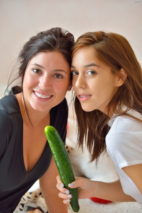 Jonge roodharige tiener met parmantige tieten speelt poesje met komkommer in de keuken