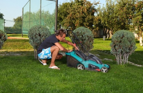 Blonde vrouw verkleedt zich in rode latex laarzen voordat ze een man op een grasveld domineert