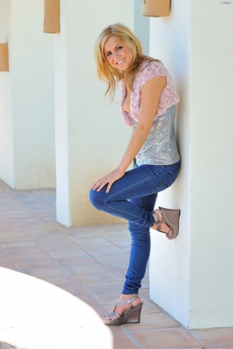 Leuke blonde tiener trekt haar blauwe jeans en slipje uit in openbare ruimte