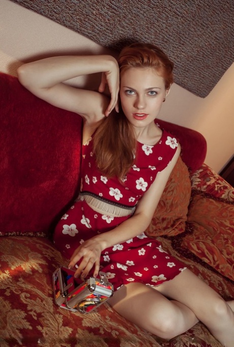 Una bella teenager glamour annoiata si esercita in pose da modella nuda sul divano