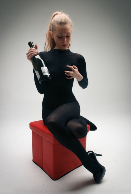 Fetisjmeisje Areana Fox in kruisloze catsuit propt een wijnfles in haar kutje