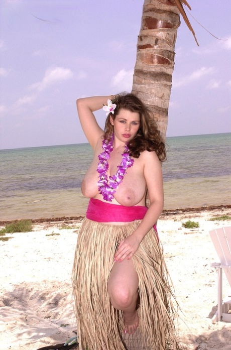 Big titted chick Desirae exposes herself on a tropical beach in a grass skirt