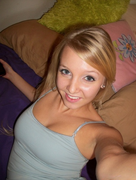 Sød teenagepige med blondt hår viser sin hårløse fisse frem på sengen