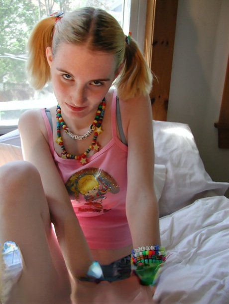 Молодая девушка-рейвер Сверчок надевает браслеты, раздеваясь на кровати