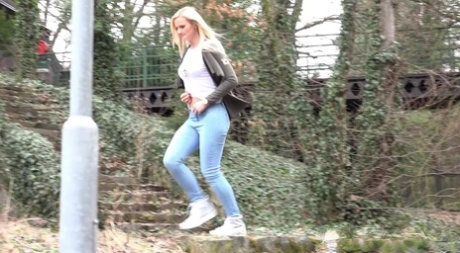 Junges Mädchen mit langen blonden Haaren Katy Sky zieht ihre Jeans herunter, um draußen zu pinkeln