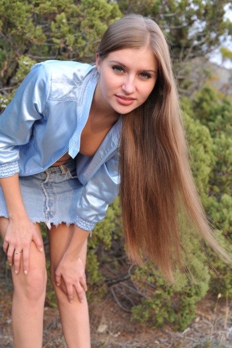 Slim Russian girl poses naked in high heels on scrubby ground