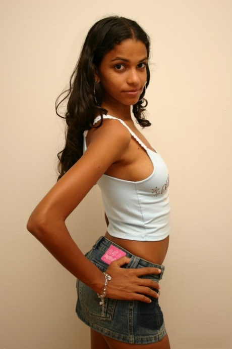 Polliana, une amatrice latina, couvre ses seins nus avec une main dans une mini-jupe en jean.