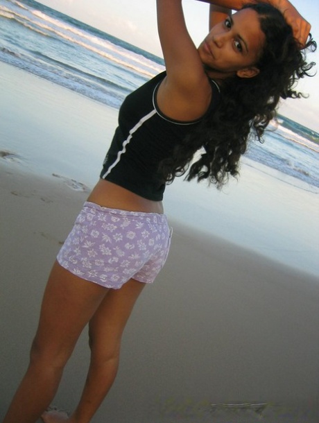 A rapariga brasileira descalça Polliana levanta a sua camisola de alças na praia