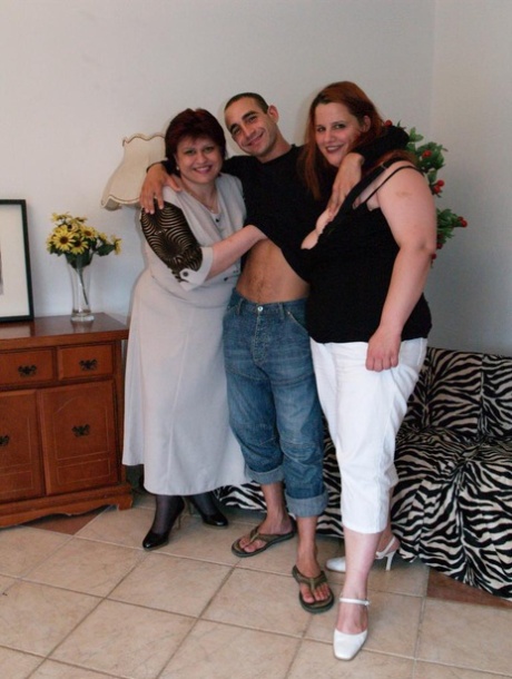 Mujeres obesas hacen un trío con un joven delgado en un sofá