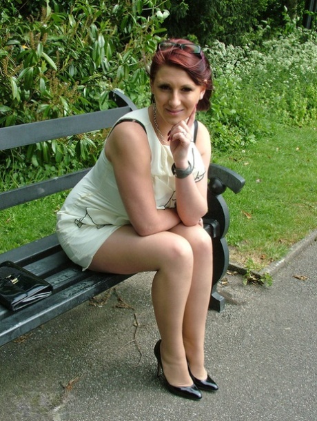 Dicke Frau mit Brille zeigt ihre Stiletto-Absätze auf einer Parkbank