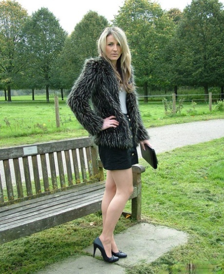 Fotomodell poserar på en lantlig bänk i svart kjol och pumps