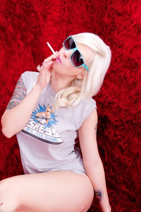 Getatoeëerde blonde Lynn Pops rookt een sigaret voordat ze masturbeert met een speeltje