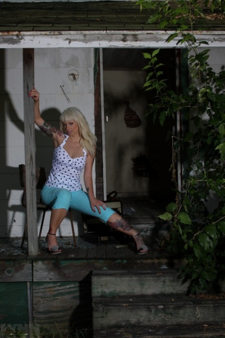 Сексуальная блондинка с татуировками Линн Попс раздевается на заднем дворе заброшенного дома