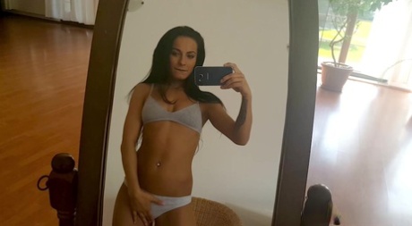 A rapariga morena Lexi Dona tira selfies ao espelho enquanto mostra as mamas e a rata