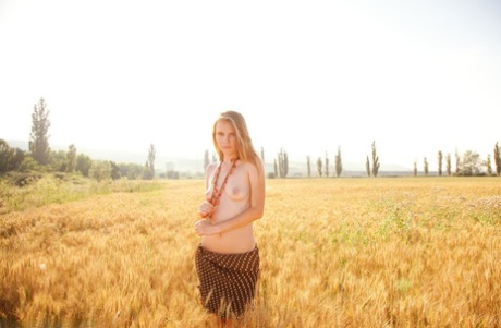 Jonge blonde schoonheid Frida C modelleert naakt in een graanveld