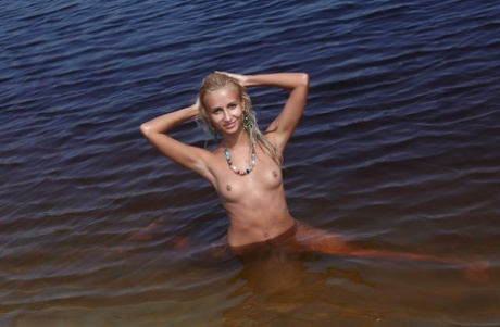 Blond Russisch meisje Afina poseert helemaal naakt op het strand en in het water