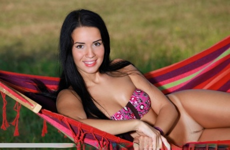 Dark haired teen Lola Marron shows off her tan lined body outside on a hammock