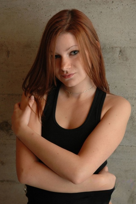 若い赤毛のKorina Blissは、裸のおっぱいに手を置きます。
