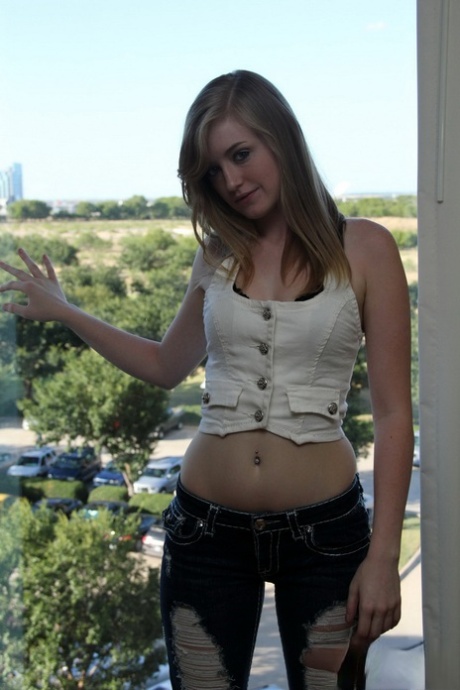 Młoda blondynka z małymi cyckami Mandy Roe ściąga dżinsy w oknie topless