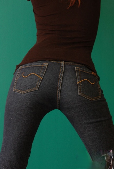 Den naturliga rödhåriga Korina Bliss täcker sina nakna bröst i ett par jeans
