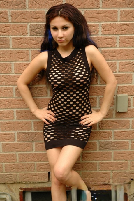 Petite teen with a wild look to her removes mesh dress to pose naked outdoors