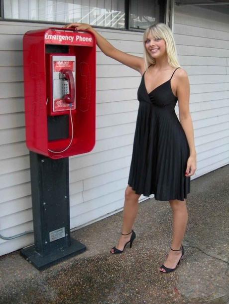 La blonde amateur Jana Jordan exhibe sa culotte devant un téléphone public.