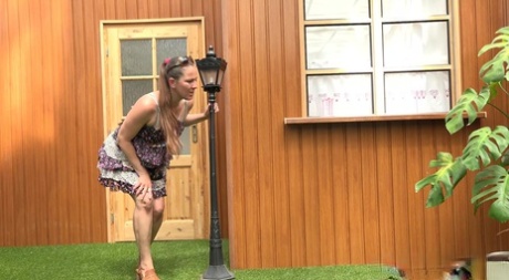 Blond kvinna Nicol D går i kort klänning för att kissa stående bakom huset