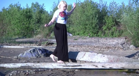 De langbenige blonde Nura gaat op het strand op het drijfhout zitten pissen.