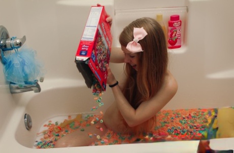 Das junge Mädchen Dolly Little leert eine Schachtel Müsli in ihr Badewasser