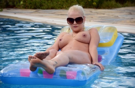 Natuurlijke blonde Kelly Fox ligt op een luchtbed met alleen een zonnebril op