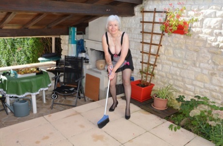 Kåt mormor lyfter sin sexiga kjol för att leka med sin bäver i trädgården