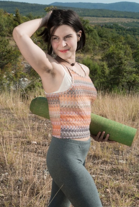 La dilettante Ole Nina, tutta naturale, si sdraia su un tappetino da yoga sotto il cielo limpido in cima a una collina.