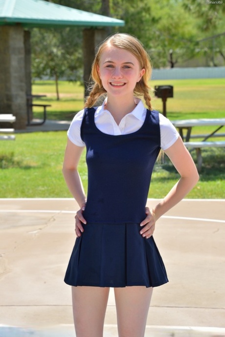 A pequena colegial Sharlotte em curvas uniformes para uma camisa de cima nua no exterior