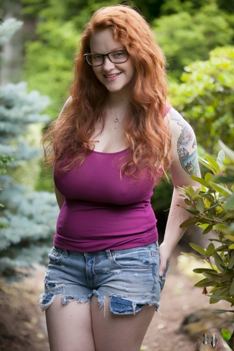 自然的红发少女在树林中暴露了她厚实的身体和下垂的大乳房