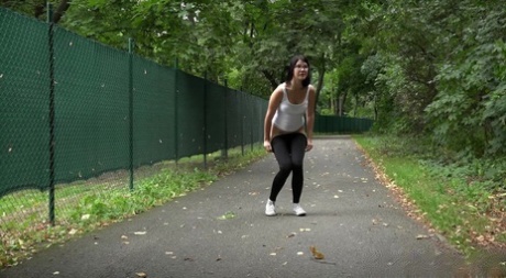 Une fille portant des lunettes baisse son legging pour pisser sur un terrain pavé.