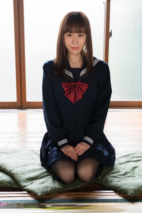 Japanse studente bevrijdt haar slanke lichaam uit haar schooloutfit op een kussen