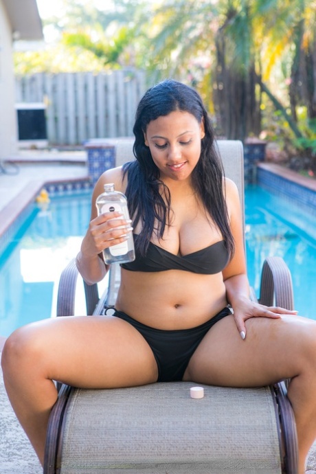 Mollige schwarze Amateurin zieht ihren Bikini aus und posiert nackt auf einem Stuhl am Pool