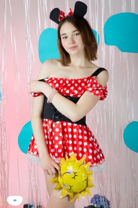 Une jeune fille de petite taille pose nue, portant uniquement les oreilles de Minnie Mouse.