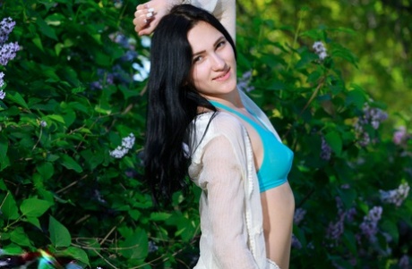 Dark haired teen Lika gets totally naked in front of blooming bushes