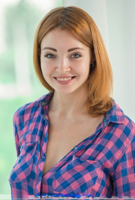 Het sexy witte meisje met aardige glimlach verwijdert denimborrels en bloesje voor naakt poseert