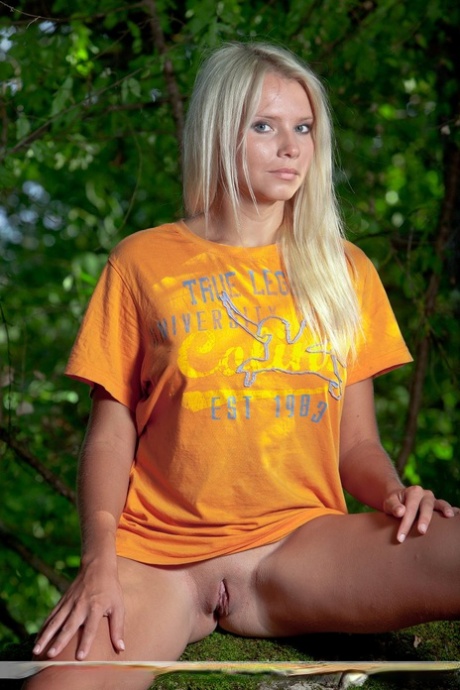 Die naturblonde Erra D zieht ein T-Shirt aus, um nackt in einem Baum zu modellieren