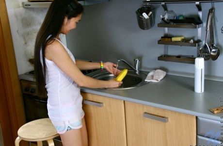 Søt asiatisk tenåring søler melk på puppene mens hun onanerer på kjøkkenet sitt